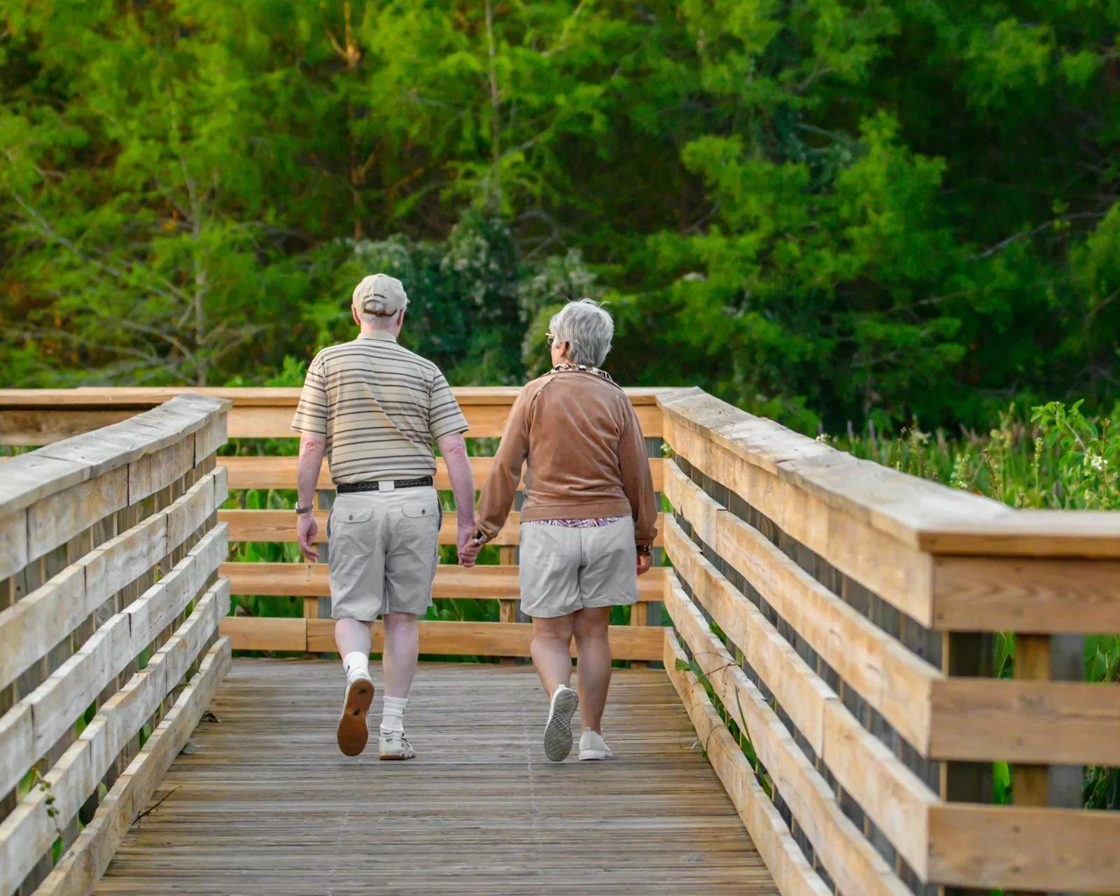 Two people walking across a bridge outdoors
